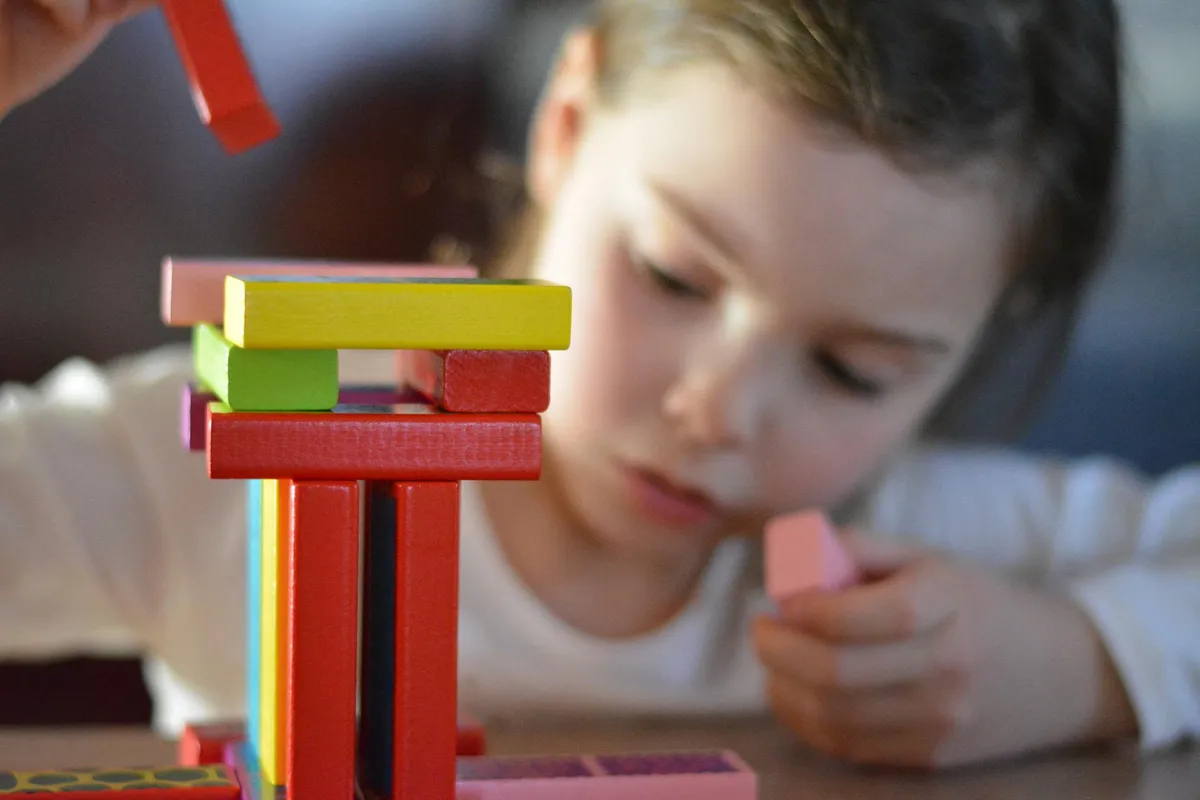 Child playing with colored building blocks during an ABA session